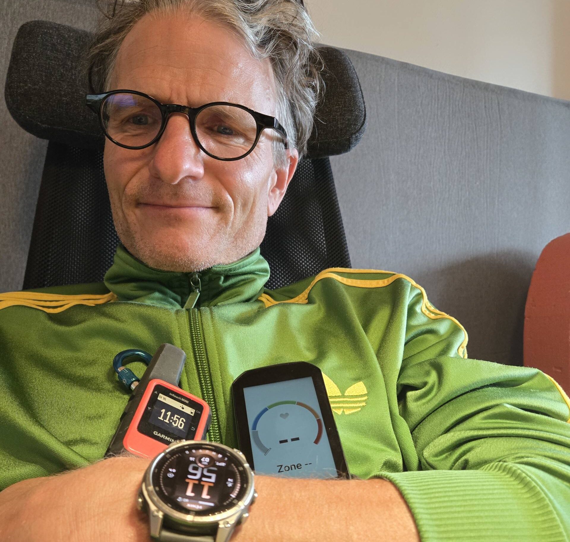 Marc Böhler mit Garmin Tabs: Eine Garmin Fenix Smartwatch (Gesundheits- und Aktivitätstracking), ein Garmin InReach Mini (Satelliten-Notfallkommunikation) und ein Garmin Edge Velocomputer (Leistungsdaten für Radfahrer). Die Geräte symbolisieren vernetzte, alltagsintegrierte Technologie für Gesundheit, Sicherheit und soziale Verbindung.