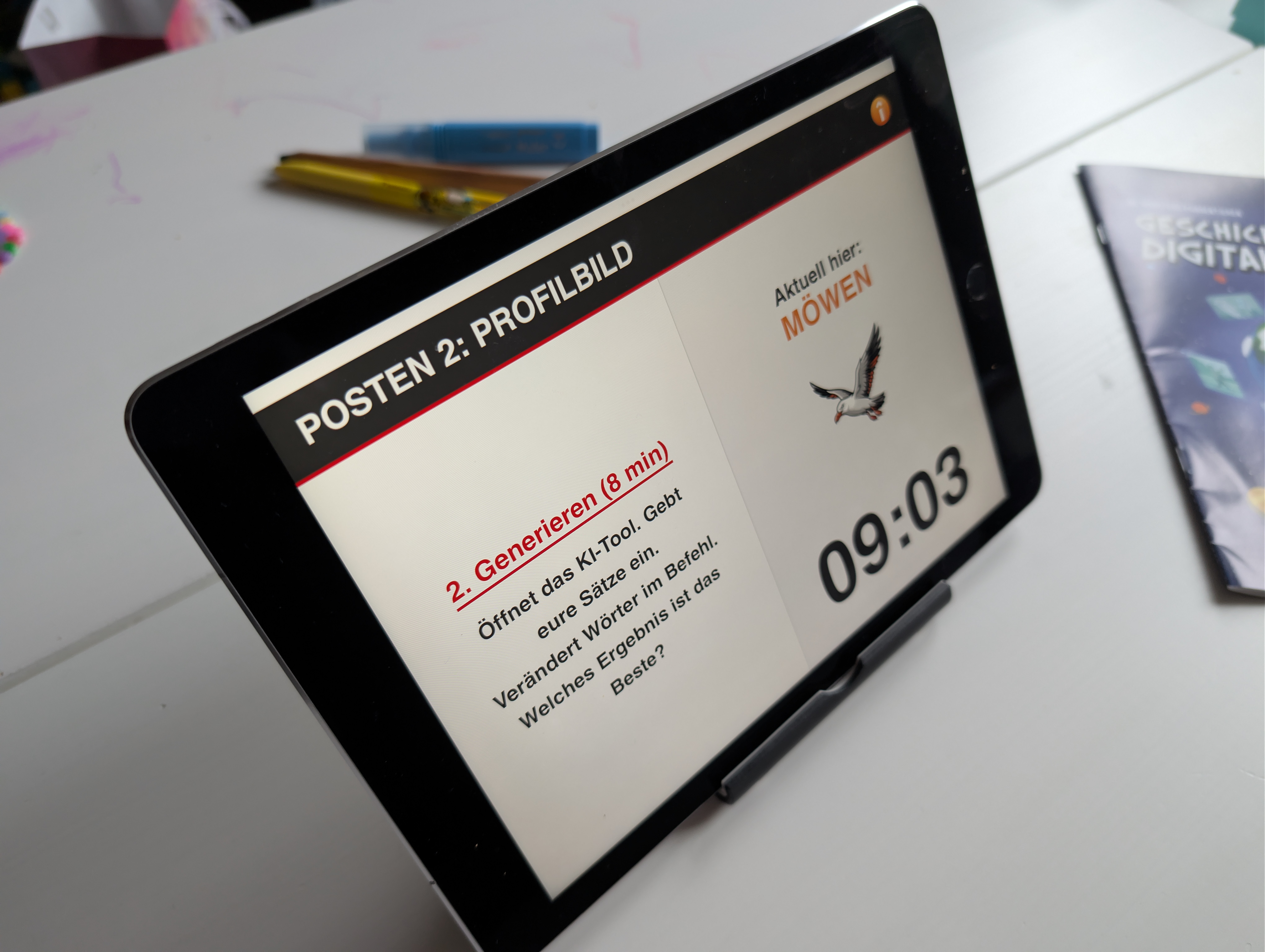 Ein Tablet zeigt die Aufgabe «Posten 2: Profilbild» im Rahmen des Medienkurses «Medien master für die 5. und 6. Primarschulstufe. Zu sehen ist der Arbeitsauftrag zum Generieren von «Möwen»-Bildern mit einem KI-Tool.