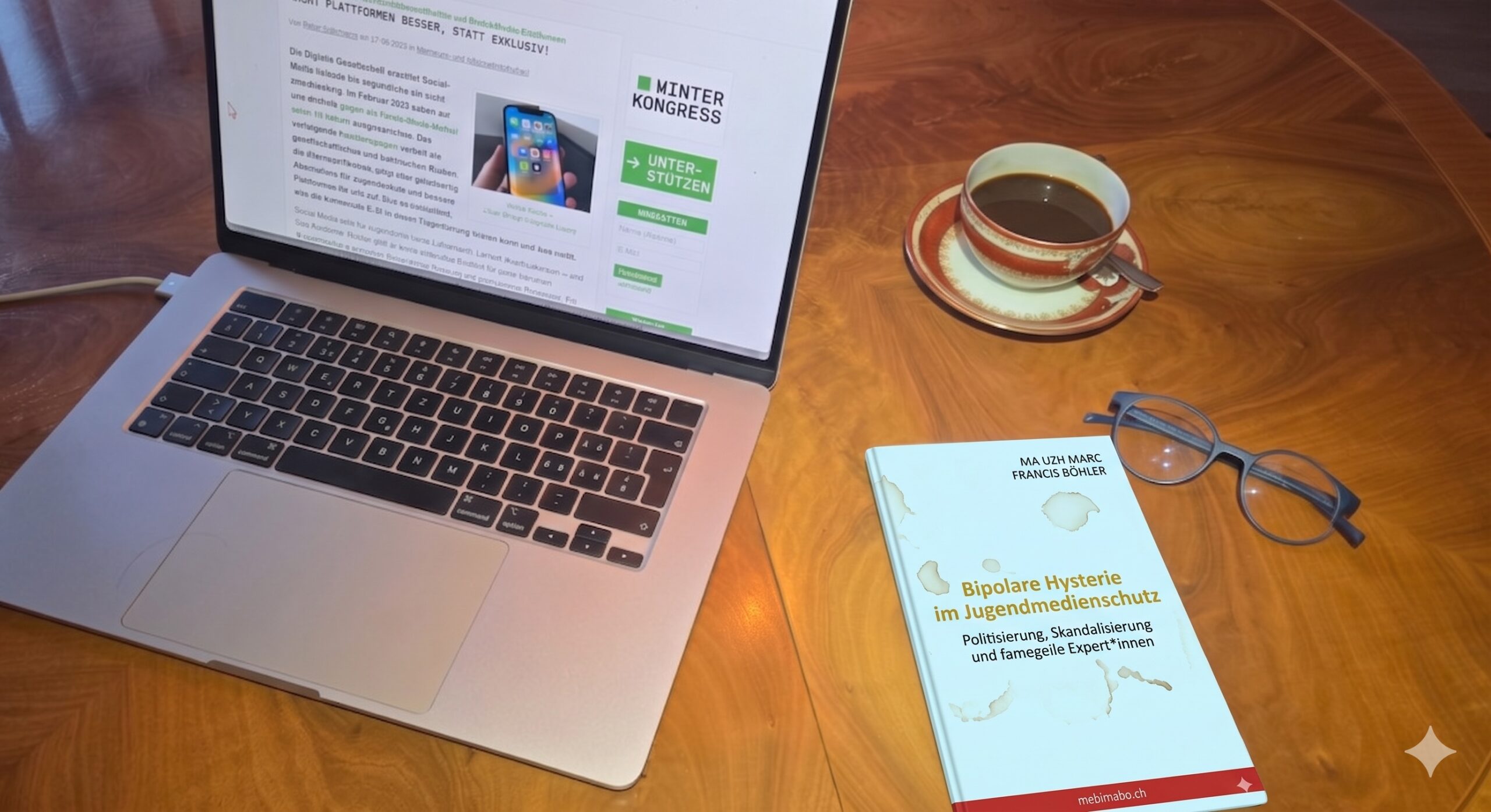 Ein fiktives Essay-Buch mit dem Titel «Bipolare Hysterie im Jugendmedienschutz» liegt auf einem Holztisch neben einer Kaffeetasse, einer Brille und einem Laptop, auf dem die Website der Digitalen Gesellschaft geöffnet ist.